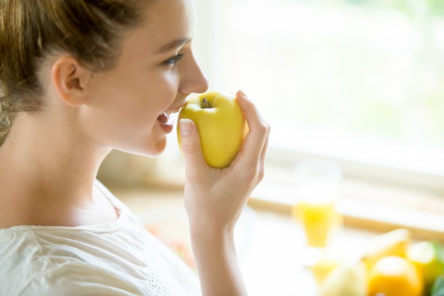 Mujer comiendo manzana para limpiar sus dientes