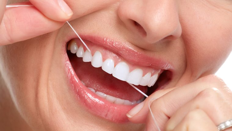 Chica haciendo uso del hilo dental