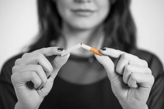 Mujer rompiendo un cigarro, para tener una buena higiene bucal