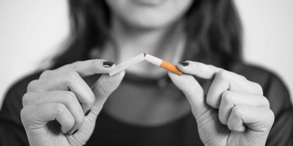 Mujer rompiendo un cigarro, para tener una buena higiene bucal