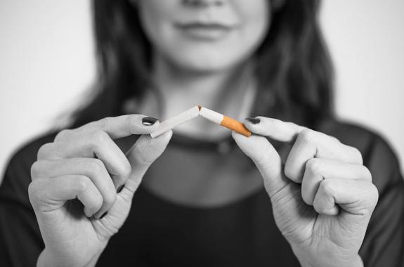 Mujer rompiendo un cigarro, para tener una buena higiene dental - Clínica dental en Gertxo
