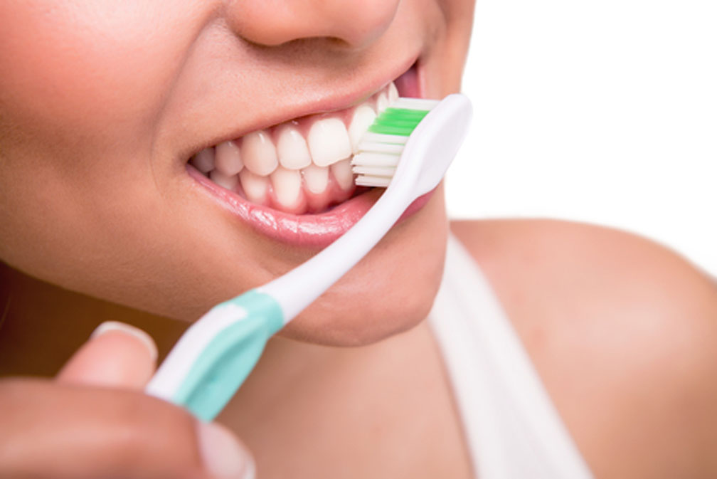 Mujer cepillándose los dientes para tener una buena higiene dental - Dentista en Gertxo